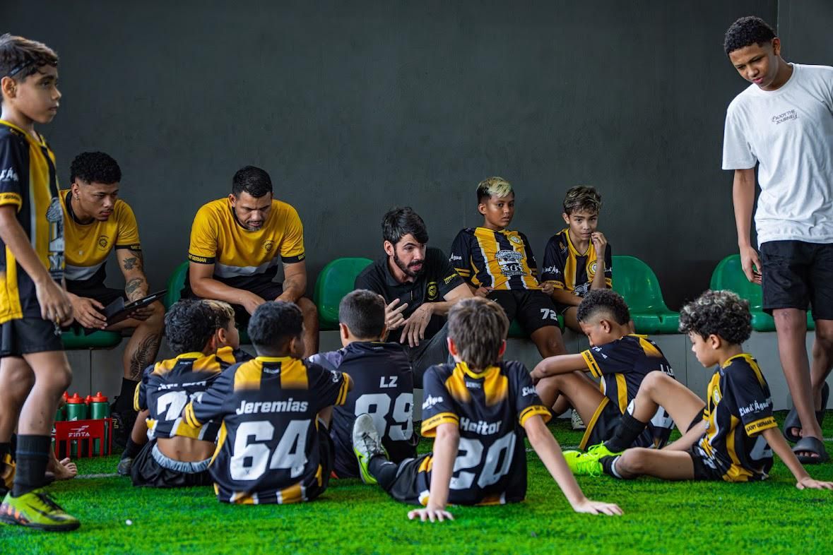 Atletas sentados em roda ouvindo os professores