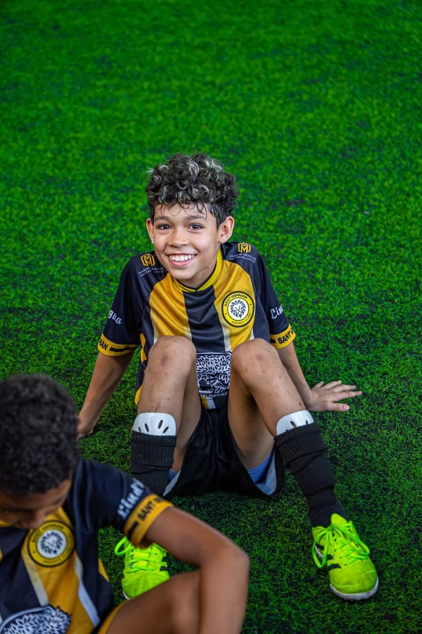 Atleta sorrindo sentado no gramado
